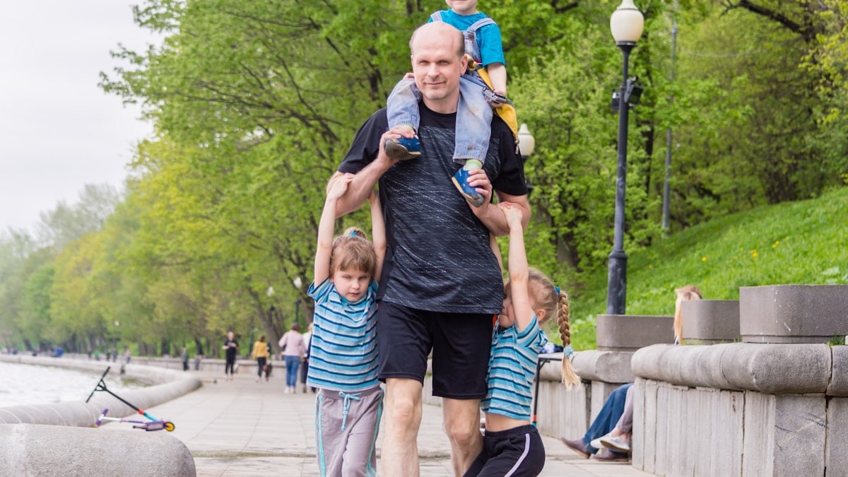 dad walks with three kids together in the park